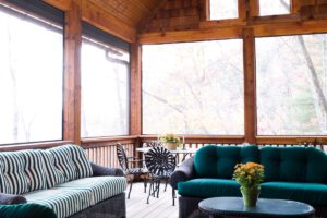 screened-in porch with sofa chairs, table and flowers